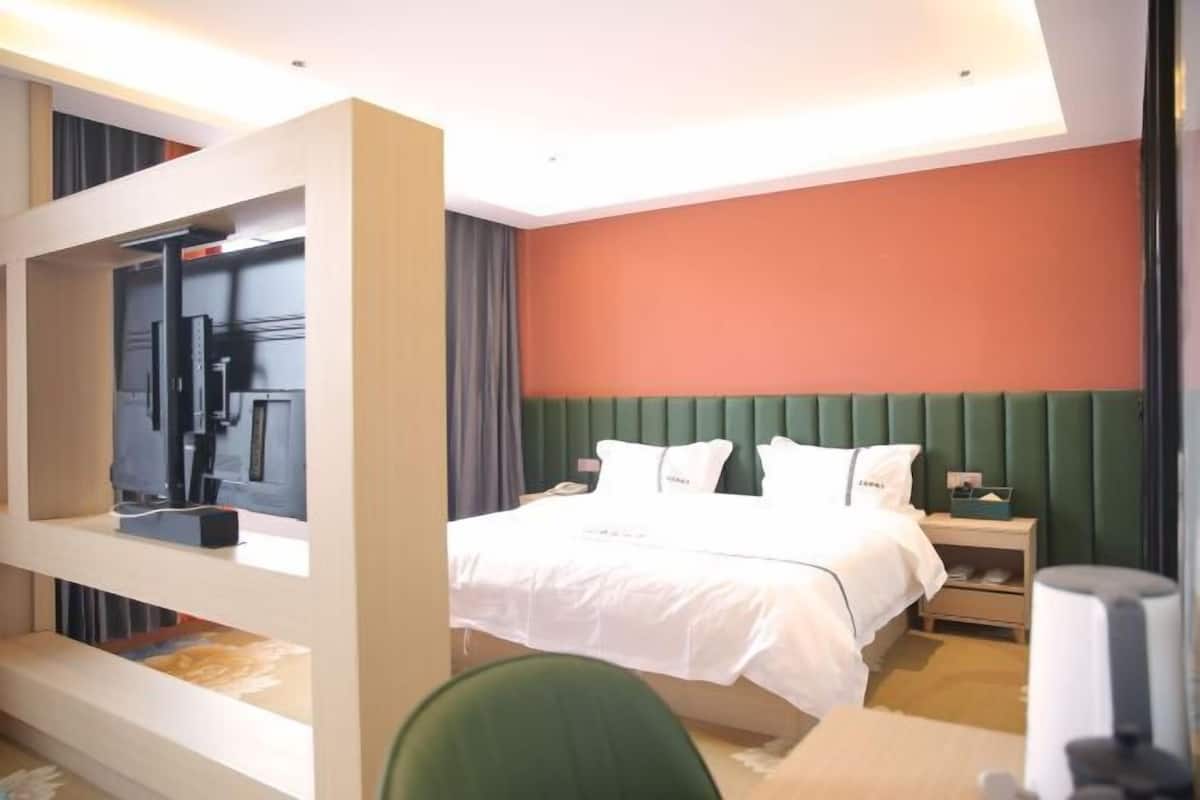 Ein Hotelzimmer mit Bett, Schreibtisch, Stuhl, Nachttisch und Fernseher.