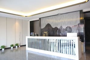 A reception desk with a modern design, a vertical panel wall, and a clean, polished floor. - Mingyangxuan Fashion Hotel (Tianjin Tucheng Subway Station) (Tianjin)