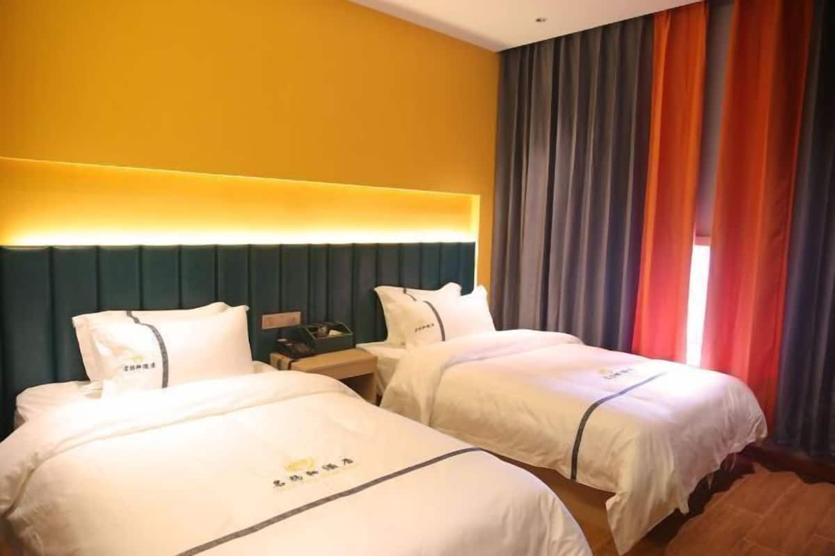 Ein Hotelzimmer mit zwei Betten, einem Nachttisch und einem fenster mit Vorhängen.