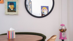 A dining area with a wooden table, green upholstered chairs, and a gumball machine. - The Hutt, 2BR Chic Condo by Velvet Ditch Villas (Oxford)