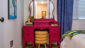 A pink vanity with a mirror, a stool, and a small shelf with books and a decorative item. - The Hutt, 2BR Chic Condo by Velvet Ditch Villas (Oxford)