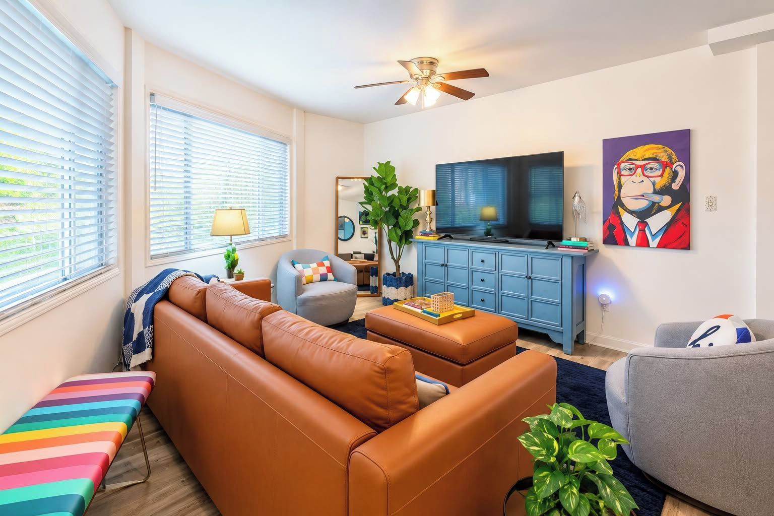 A living room with a sofa, armchair, ottoman, and a television.