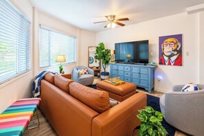 A living room with a sofa, armchair, ottoman, and a television. - The Hutt, Walk to Campus, by VelvetDitchVillas (Oxford)