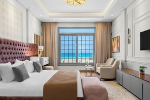 Une chambre d’hôtel avec un grand lit, une chaise, un bureau, une télévision et une vue sur la plage.