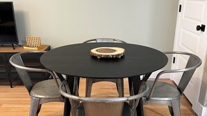 Ein runder Tisch mit einem Holzuntersetzer, umgeben von vier Stühlen mit gebogenen Rückenlehnen.