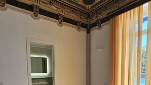 A hotel room with a bed, a chair, a bathroom with a sink, and a view of the outdoors. - Galene - Beachfront in Costa d'Amalfi (Maiori)