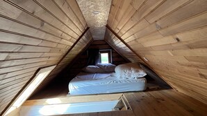 A small, sloped-roofed attic bedroom with a single bed and a skylight.