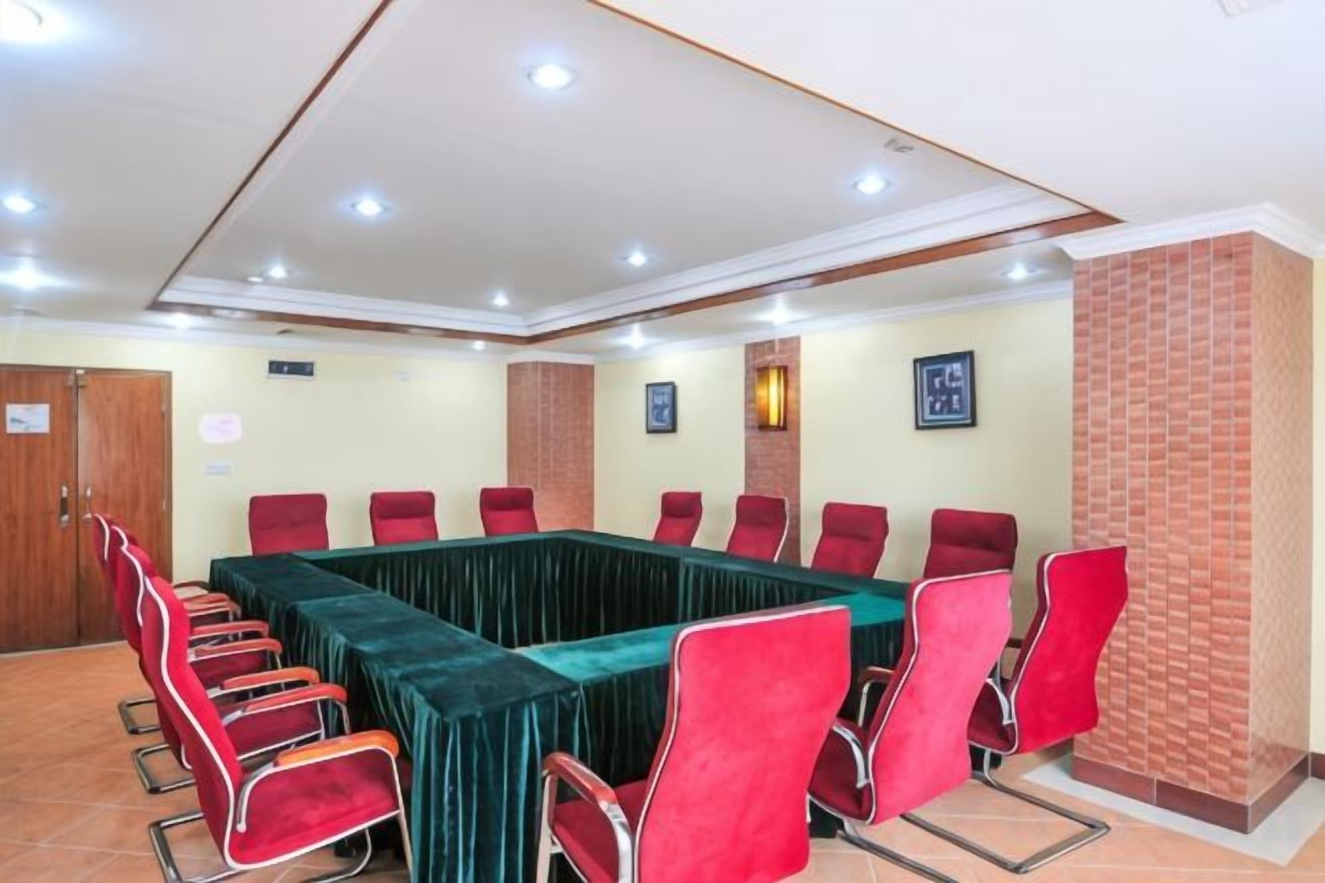 A conference room with a rectangular table and red chairs.