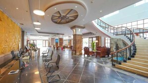 A spacious lobby with a curved staircase, a reception desk, and seating areas. - Xinxing Garden Hotel (Sanyawan) (Sanya)