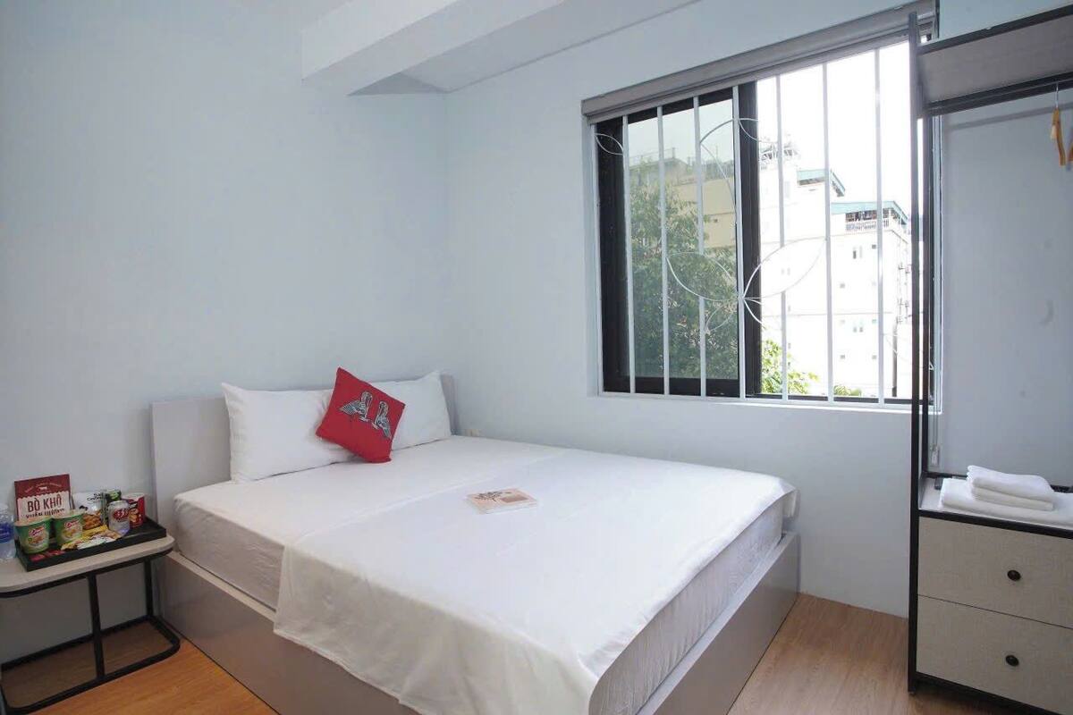 A bedroom with a bed, a nightstand, a window, and a dresser.