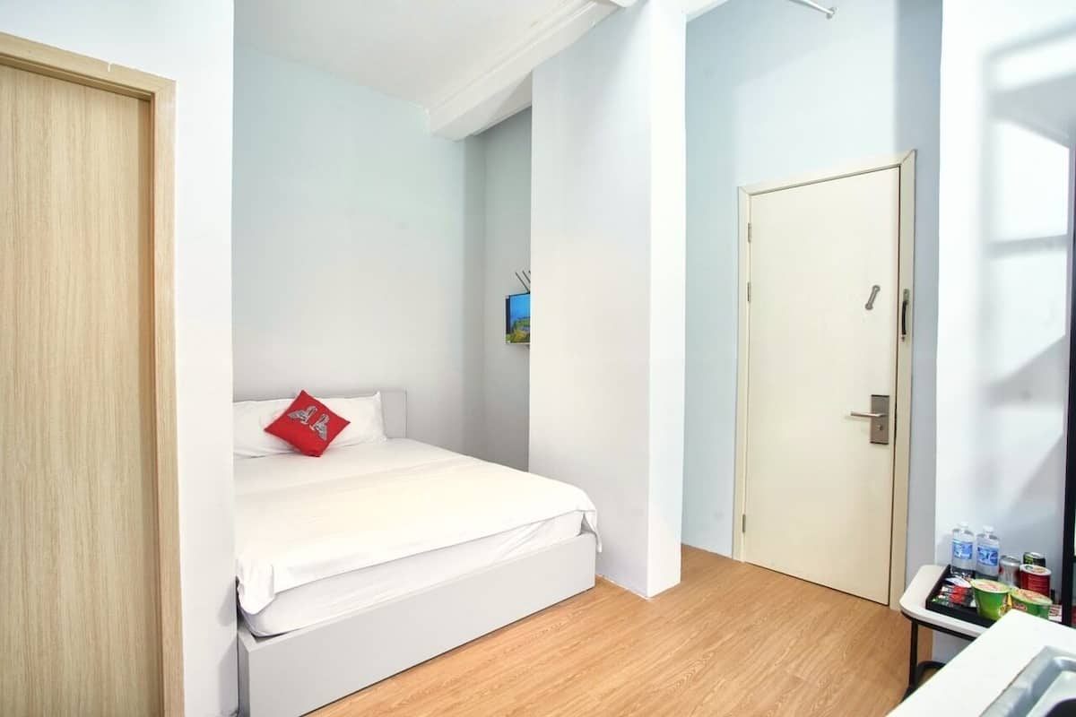 A bedroom with a bed, a door, and a small table with bottles.