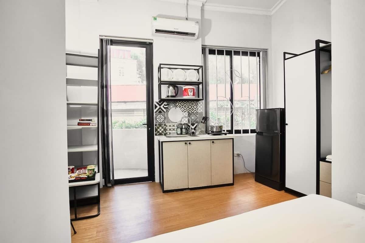 A compact kitchen with a built-in stove, a black refrigerator, and a window with blinds.