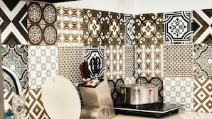 A kitchen with patterned tiles, a sink, a dish rack, a pot on the stove, and a bottle of dish soap. - Eco Nest Hotel & Apartment (Hanoi)