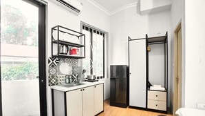 A compact kitchen with a sink, countertop, and a black refrigerator. There is a window with a view of greenery outside. - Eco Nest Hotel & Apartment (Hanoi)