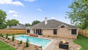 A backyard with a swimming pool, a fire pit, and a covered patio area. - Extraordinary Pool Villa - Outdoor Fun, Near Stadiums (North Richland Hills)