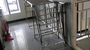 A metal drying rack in a room with a tiled floor and a door to the right.
