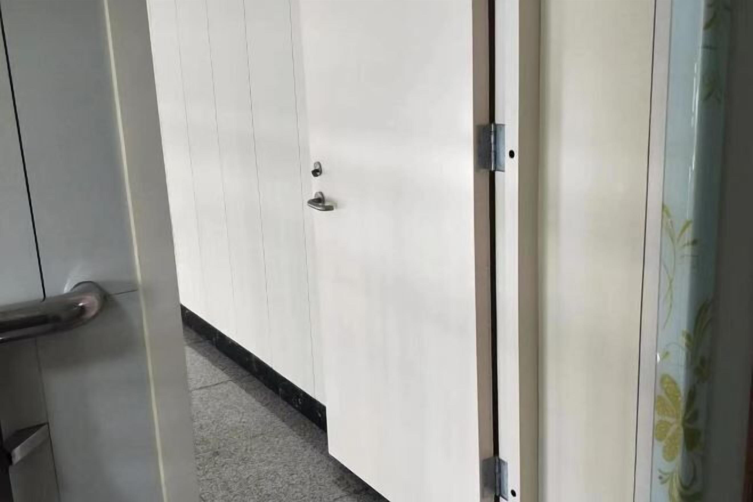 A door with a metallic handle and a keyhole, leading to a room with a tiled floor.