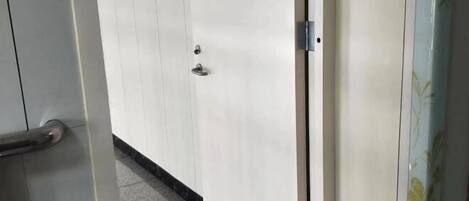 A door with a metallic handle and a keyhole, leading to a room with a tiled floor.