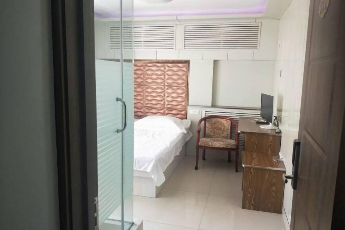 A bedroom with a bed, a chair, a desk, and a television.