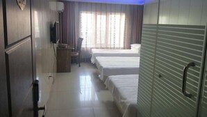 Une chambre d’hôtel avec deux lits, une télévision, un bureau et une fenêtre avec des rideaux.