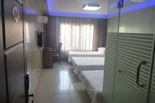 Habitación de hotel con dos camas, televisor, escritorio y ventana con cortinas.