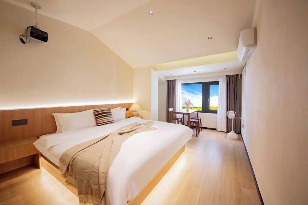 Een hotelkamer met een groot bed, een bureau en uitzicht op de omgeving.