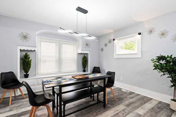 A dining area with a black table, four chairs, and a potted plant.