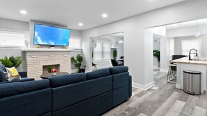 Una sala de estar moderna con un televisor grande, una chimenea y un comedor.