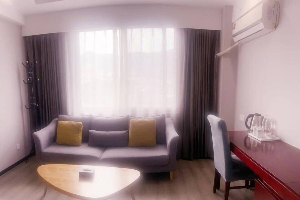 A modern living room with a grey sofa, a wooden coffee table, and a red desk with a chair.
