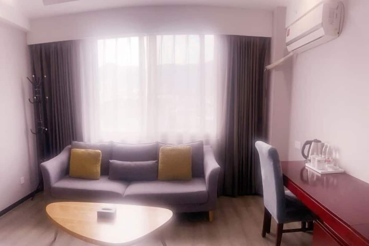 A modern living room with a grey sofa, a wooden coffee table, and a red desk with a chair.