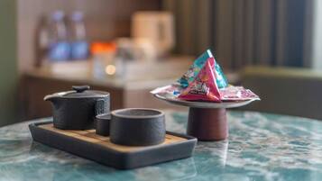 A table with a teapot, cups, and a packet of snacks.