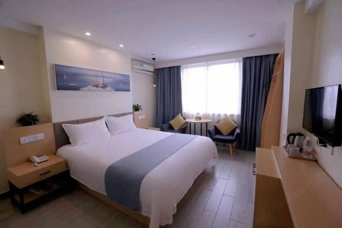 A hotel room with a bed, bedside table, TV, and a small table with chairs.