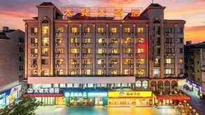 Un hôtel à plusieurs étages, reconnaissable à son enseigne bien visible au sommet, doté de nombreux balcons et d’une entrée au niveau du sol, avec des boutiques.