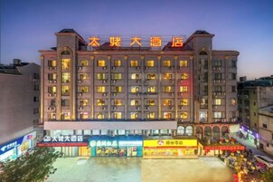 Un hotel de varios pisos con una entrada destacada y varias tiendas a nivel de calle.