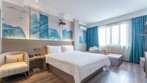 Une chambre d’hôtel moderne, dotée d’un grand lit, d’un canapé, d’un bureau et d’une fenêtre avec des rideaux.