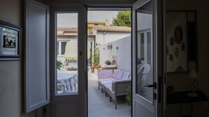 An open door leading to a patio with a table, a sofa, and a potted plant.