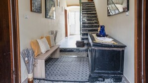 A hallway with a wooden bench, a black cabinet, and a patterned floor.