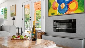 Un salon moderne avec une table basse en marbre, une bouteille de vin et un plateau de fruits.