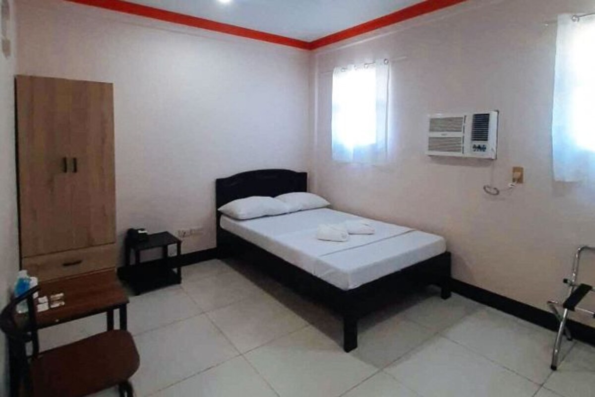 A bedroom with a bed, a wardrobe, a desk, and a chair.