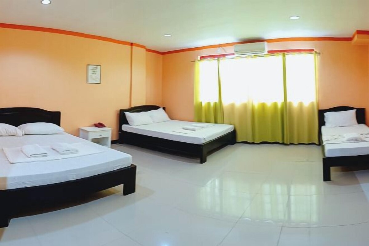 A hotel room with two beds, a nightstand, and a window with curtains.