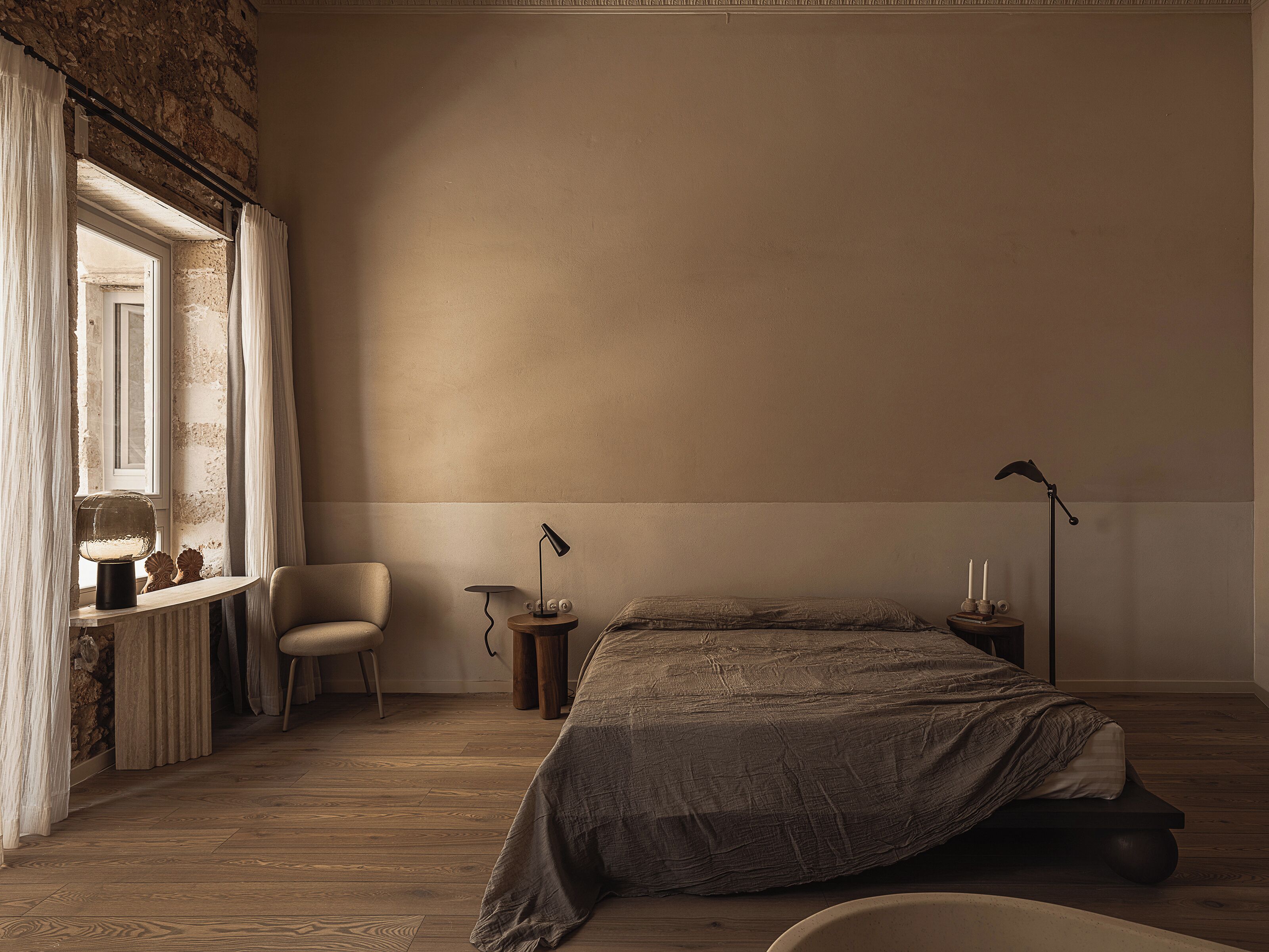 A bedroom with a bed, a chair, a desk, and a lamp.