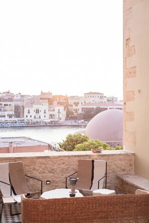 Terraço com mobiliário de vime e vista para um horizonte urbano com edifícios e uma grande estrutura em cúpula.