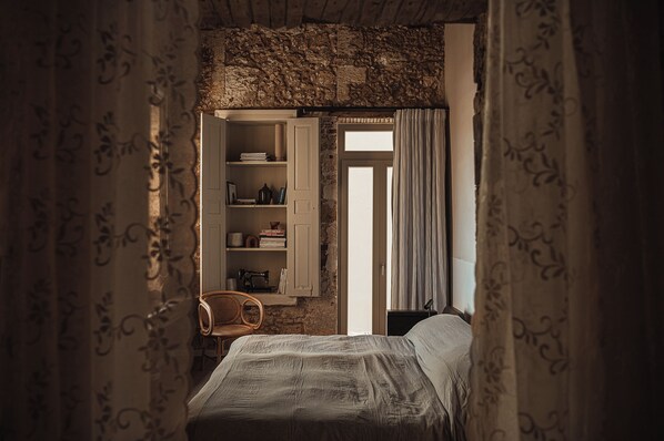 Quarto com cama, cadeira, guarda-roupa e janela.