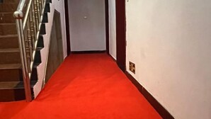 Ein Flur mit rotem Teppich, einer Treppe mit Metallgeländern und einer weißen Wand.
