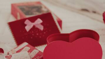 A bed with neatly arranged red and white items, including heart-shaped boxes and a book titled "24 questions tout savoir".