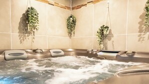 A bathroom with a hot tub, tiled walls, and hanging plants. - Suite soledad (Maraussan)