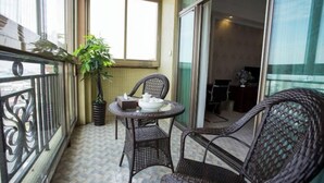A balcony with wicker furniture, a potted plant, and a table with a teapot and cups. - Houten Hotel (Shantou)