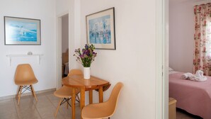 A room with a wooden dining table, two chairs, a vase with flowers, and two framed pictures on the wall. - Marias Hospitality.Pure Paroshospitality (ΠΑΡΟΣ)