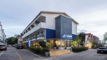 Un hotel moderno con una entrada destacada, varios pisos y un balcón visible.