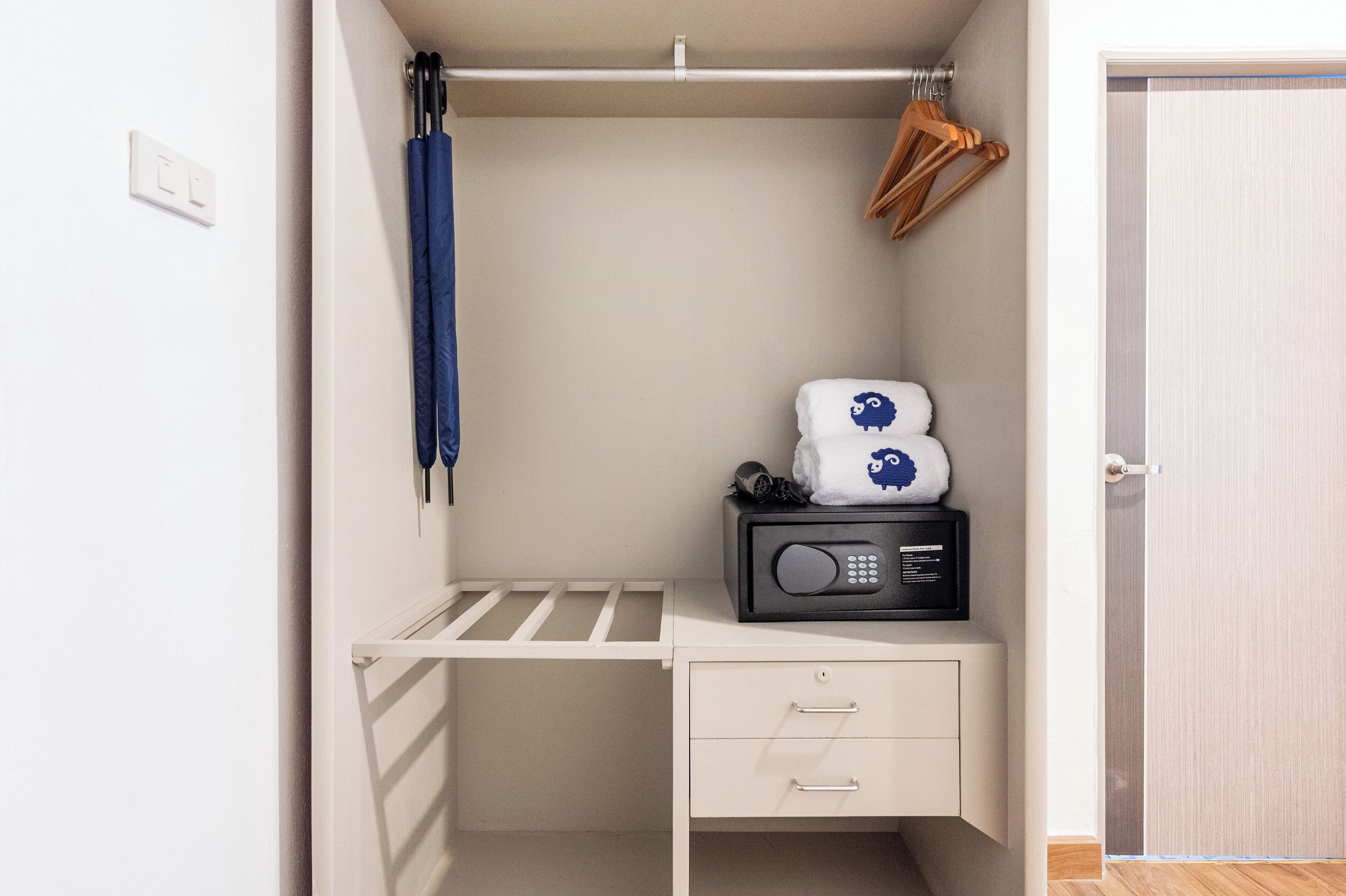 Un meuble de rangement compact comprenant un micro-ondes, une petite étagère et un espace pour suspendre des vêtements.